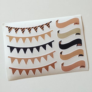 May include: A sheet of decorative stickers featuring pennant banners and ribbon shapes in various colors and patterns. The banners have alternating patterns of stripes, dots, and plaid. The ribbons are solid colors with patterned accents.