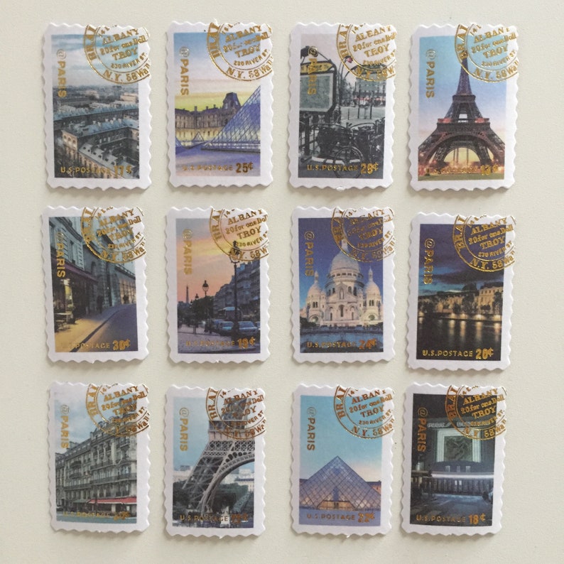 May include: Twelve vintage postage stamps featuring images of Paris, France. Each stamp has a gold circle with the text "ALBANY 20 for charity TROY N.Y. 58 W" and "@PARIS". The stamps feature images of the Eiffel Tower, the Louvre, the Sacr&eacute;-C&oelig;ur Basilica, and other Parisian landmarks.