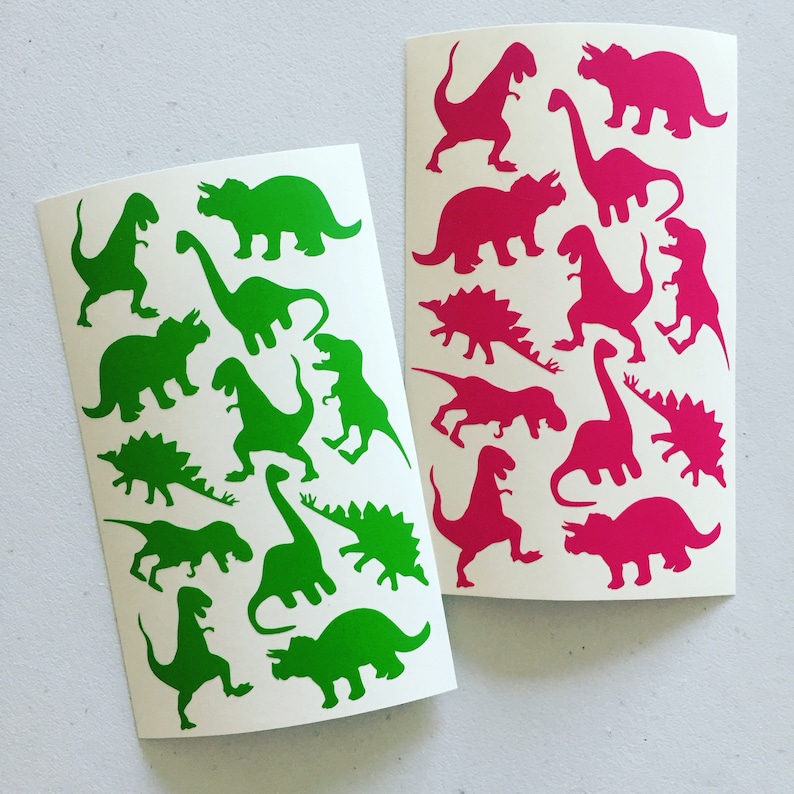 May include: Two sheets of white paper with dinosaur silhouettes. One sheet has green dinosaurs and the other has pink dinosaurs.