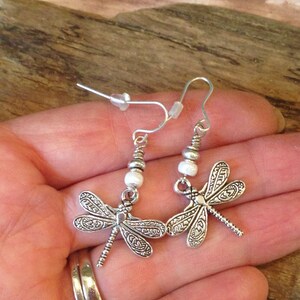 May include: Silver dragonfly earrings with white beads and silver hooks.