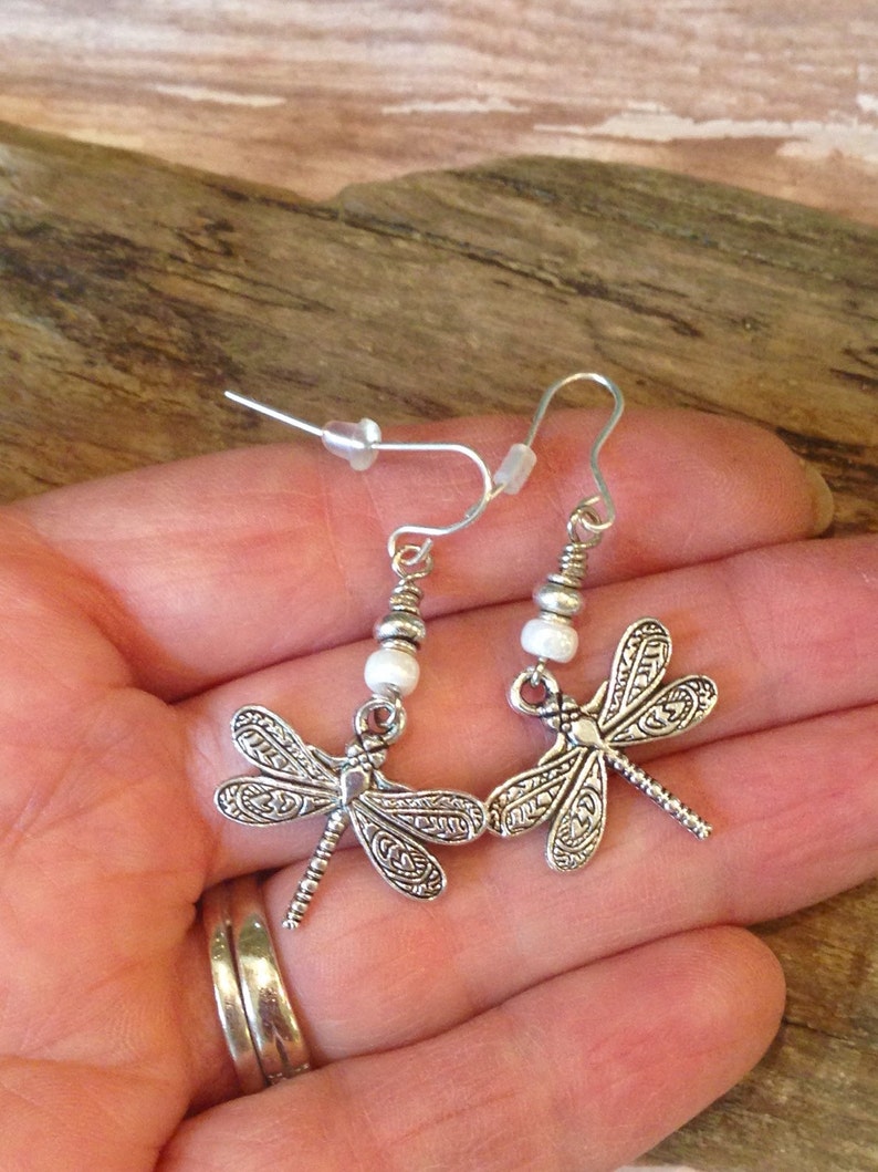 May include: Silver dragonfly earrings with white beads and silver hooks.