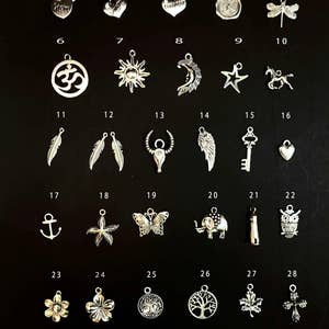May include: A set of 28 silver charm pendants with various designs, including hearts, stars, animals, and symbols. The charms are arranged in rows on a black background.