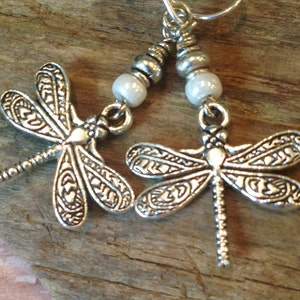 May include: Silver dragonfly earrings with white pearl beads and silver hooks.