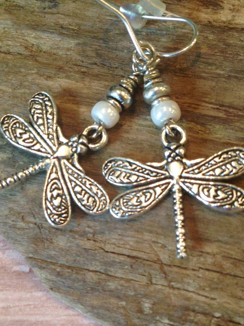 May include: Silver dragonfly earrings with white pearl beads and silver hooks.