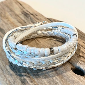 Puede incluir: Pulsera de cuero blanco con cuentas blancas y detalles plateados.