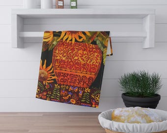 May include: A decorative kitchen towel featuring a vibrant floral design with sunflowers and a large orange vase. The towel is hanging on a white shelf above a wooden countertop. The design includes intricate patterns and a dark background.
