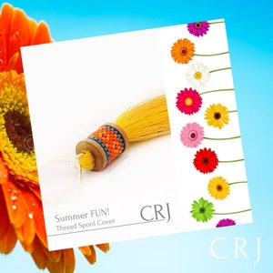 May include: A yellow thread spool cover with a colourful beaded design and a long yellow tassel. The text "Summer FUN! Thread Spool Cover" is below the spool cover. The letters "CRJ" are in the top right corner of the image.