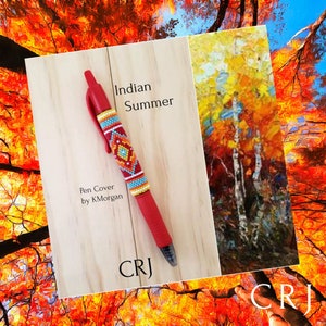 May include: A red pen with a beaded pen cover featuring a colorful geometric design. The pen cover is labeled "Indian Summer" and "Pen Cover by KMorgan". The image also includes a painting of a fall scene with trees in shades of yellow, orange, and red.