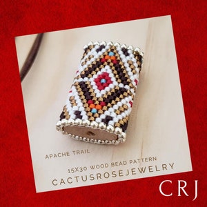 Op de afbeelding: Een rechthoekig houten kralenpatroon met een geometrisch ontwerp in witte, zwarte, gouden, rode en turquoise kralen. De tekst "Apache Trail" en "CACTUSROSEJEWELRY" zijn zichtbaar. Het kralenpatroon meet 1,5 cm x 3 cm.