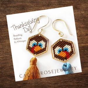 May include: Thanksgiving Day Beading Pattern by K.Morgan.  A pair of gold earrings with a beaded turkey design.  The earrings are hexagonal shaped and feature a brown, white, orange, red, and blue beaded design.