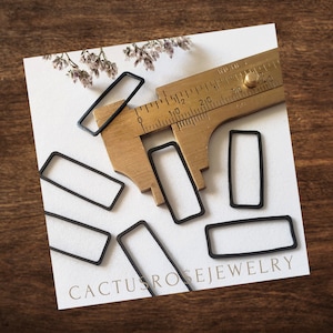 May include: Six black metal rectangular frames of varying sizes, measured with a brass ruler. The ruler reads "Inches" and has markings up to 40. The frames are on a white surface with the text "Cactus Rose Jewelry" in black.