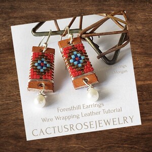 Pode incluir: Um par de brincos de couro feitos à mão com contas vermelhas, azuis e douradas. Os brincos são envoltos em fio de prata e têm um charme de pérola pendurado em cada um. Os brincos são etiquetados como "Foresthill Earrings Wire Wrapping Leather Tutorial CACTUSROSEJEWELRY".