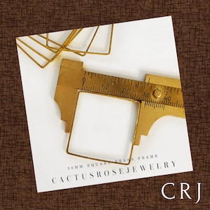 May include: A close-up of a brass square frame measuring 30 mm, with a ruler used to show the size. The frame is part of a set of brass frames for jewellery making. The text "Cactusrosejewelry CRJ" is printed on the white surface below the frame.