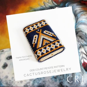 Op de afbeelding: Een blauwe en oranje kralenbeurs met een geometrisch patroon. De beurs is gemaakt met een oneven peyote-steek. De tekst "Twin Feathers Kmorgan" en "Odd Count Peyote Pattern Cactusrosejewelry CRJ" is onder de beurs gedrukt.