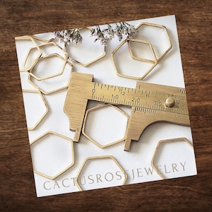 May include: A close-up of a set of gold-toned metal hexagon shapes, with a ruler measuring one of the shapes. The text "Cactusros Jewelry" is visible in the bottom right corner of the image.