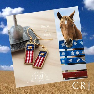 May include: A pair of gold-toned earrings with red, white, and blue beaded American flag designs. The earrings are labeled "Spirit of Liberty" and "Cactus Rose Jewelry CRJ".
