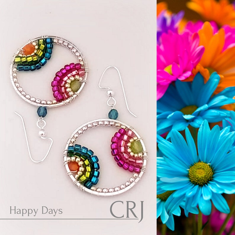 May include: Rainbow-colored beaded earrings with silver hoops and hooks. The beads are arranged in a circular pattern, creating a colorful and eye-catching design. The earrings are labeled "Happy Days" and "CRJ".