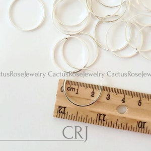 May include: A close-up of a ruler measuring a silver jump ring. The jump ring is 1 inch in diameter. The ruler is labeled "cm1" and has markings up to 5 inches.