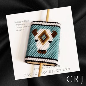 May include: A beaded peyote stitch pattern of a white buffalo with brown eyes and nose. The beadwork is on a wooden dowel and is labeled "White Buffalo - Pendant - Purse Charm - Key Fob" and "Peyote Pattern Cactus Rose Jewelry CRJ".