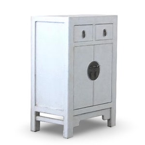 Puede incluir: Un armario de madera blanco con dos cajones y dos puertas. Las puertas tienen un recorte circular con una manija de metal. El armario tiene un diseño simple y es perfecto para un espacio pequeño.