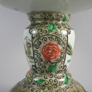 Pode incluir: Uma foto detalhada de um objeto decorativo de cer&acirc;mica branca com uma base larga e um topo alargado. O objeto &eacute; adornado com intrincados padr&otilde;es florais e de rolagem em vermelho, verde e dourado. O design inclui uma grande rosa vermelha e folhas verdes.