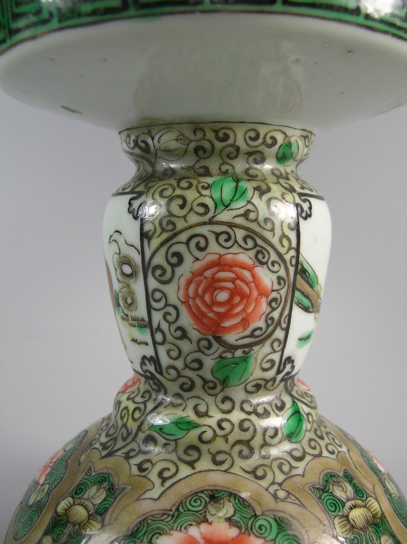 Pode incluir: Uma foto detalhada de um objeto decorativo de cer&acirc;mica branca com uma base larga e um topo alargado. O objeto &eacute; adornado com intrincados padr&otilde;es florais e de rolagem em vermelho, verde e dourado. O design inclui uma grande rosa vermelha e folhas verdes.