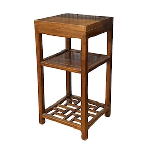 May include: A three-tiered, wooden side table with a warm brown finish. The table features a square top, a middle shelf, and a decorative, openwork base. The design is simple and elegant, suitable for various decor styles.