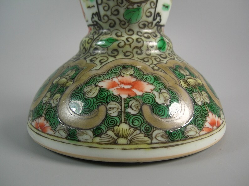Pode incluir: Close-up de um objeto decorativo de cer&acirc;mica. A base apresenta um design floral com detalhes em laranja, verde e dourado. O objeto tem uma base branca e uma forma bulbosa, com padr&otilde;es pintados intrincados.