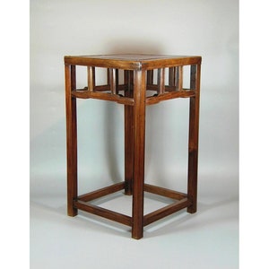 May include: A dark brown wooden side table with a square top and an open, lattice-like design on the sides. The table has a simple, elegant design.