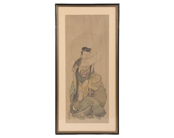 Op de afbeelding: Een ingelijste print van een traditionele Japanse schildering die een figuur in een gele robe toont die op een rots zit met een grote cirkel erachter. De figuur houdt een rol en heeft een serene uitdrukking. De schildering is uitgevoerd in tinten bruin, groen en wit.