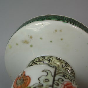 Pode incluir: Objeto decorativo de cer&acirc;mica branca com uma borda geom&eacute;trica verde. O objeto tem um topo arredondado e um design floral detalhado em laranja, vermelho e preto. O objeto &eacute; provavelmente uma pe&ccedil;a decorativa.