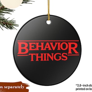 May include: A round black ceramic ornament featuring the red text BEHAVIOR THINGS printed in a stylized font. The ornament includes a gold hanging string and has a diameter of 2.8 inches with the design printed on both sides of the ceramic surface.