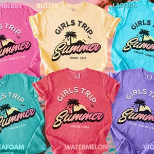 May include: Six brightly coloured t-shirts, each featuring the text "GIRLS TRIP Summer" with a tropical design. The shirts are in shades of pink, yellow, blue, teal, red, and purple. The text includes location and date details.