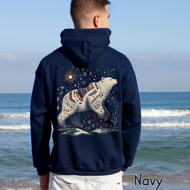 May include: Navy blue hoodie with a detailed illustration of a polar bear adorned with intricate patterns. The design includes a starry night sky, a sun, and floral elements. The word "Navy" is printed at the bottom.