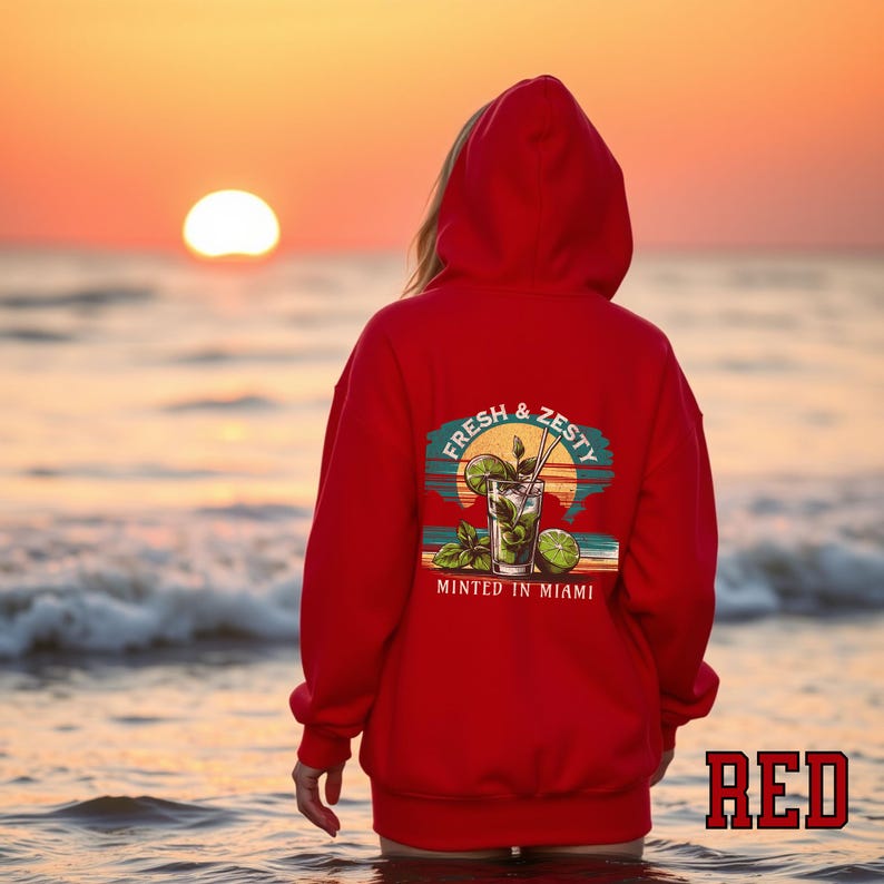 Turn up the tropical energy with our Fresh & Zesty – Minted in Miami hoodie, featuring a bold mojito graphic set against a dreamy Miami sunset beach scene. This eye-catching back print channels sunny coastal vibes, citrusy freshness, and laid-back luxury—perfect for sipping mojitos or dreaming of South Beach. A go-to for travel, lounging, or gifting anyone who loves cocktails, sunshine, and Miami heat.  Ideal gift for cocktail lovers, beachgoers, or anyone with a thing for Miami vibes.