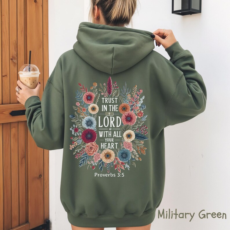 May include: Military green hoodie with floral design and the text "Trust in the Lord with all your heart" and "Proverbs 3:5". The hoodie has a drawstring hood and long sleeves.