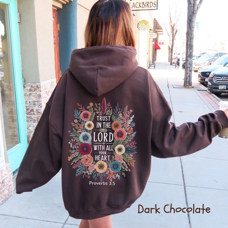 Puede incluir: Sudadera con capucha de color chocolate oscuro con un dise&ntilde;o floral en la espalda. El dise&ntilde;o incluye el texto "Trust in the Lord with all your heart" y el vers&iacute;culo b&iacute;blico Proverbios 3:5. Un estilo casual y c&oacute;modo.