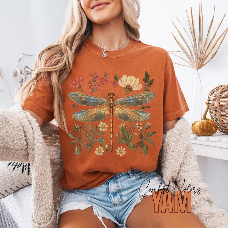 This Women's Dragonfly Floral T-Shirt is a boho and nature-inspired tee that is perfect for garden lovers and those who embrace the cottagecore aesthetic. It exudes a peaceful and whimsical vibe, making it a great addition to a nature lover's wardrobe. Ideal for casual wear or as a thoughtful gift for a loved one who enjoys botanical designs. Relevant for Earth Day, birthdays, and any nature-themed celebrations.