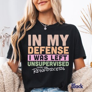 May include: Black t-shirt with the text "IN MY DEFENSE I WAS LEFT UNSUPERVISED WITH THE REINFORCERS" in various colours. The word "Black" is printed at the bottom right of the shirt.