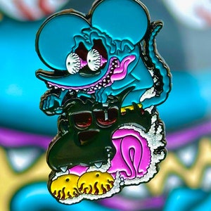 Puede incluir: Un pin de esmalte azul y negro con un monstruo de dibujos animados con una boca grande y dientes afilados. El monstruo está montado en la espalda de un monstruo negro más pequeño con ojos amarillos. El pin está en el estilo de una caricatura y tiene un acabado brillante.