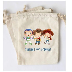 May include: Beige drawstring bags featuring cartoon illustrations of Buzz Lightyear, Woody, and Jessie. The bags have the text "Thanks For Coming!" printed in blue. The bags are made of a natural fabric.