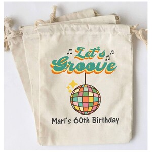 May include: A set of three white cotton drawstring bags with a retro design featuring a disco ball, musical notes, and the text "Let's Groove" in a colorful font. The bags also include the text "Mari's 60th Birthday".