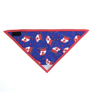 May include: A blue bandana with a red border and a repeating pattern of Canadian flags. The bandana has a velcro closure.
