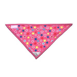 May include: Pink triangle bandana with a white border and a reflective strip. The bandana is covered in a pattern of multi-colored stars.