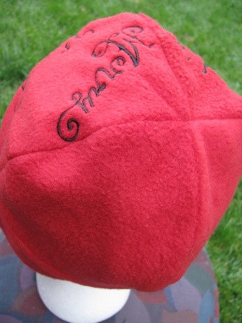 May include: Red fleece beanie with black embroidered text that reads "Embrace the Air".