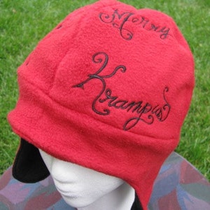 May include: Red fleece hat with black embroidered text that reads "Mommy Krampus".
