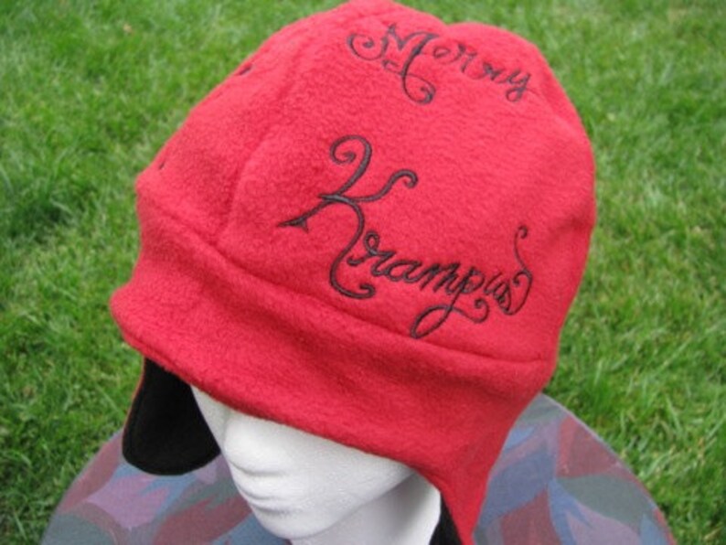 May include: Red fleece hat with black embroidered text that reads "Mommy Krampus".