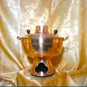 May include: A copper hot pot with black handles and a stand. The pot has a round body and a lid with a chimney.