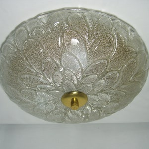 May include: A clear glass ceiling light fixture with a floral pattern and a gold metal center.