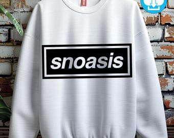 May include: White sweatshirt with the word "snoasis" in a black rectangle with a white border. The sweatshirt has a crew neck and long sleeves. A small red tag is visible near the collar. A digital download icon is in the upper right corner.